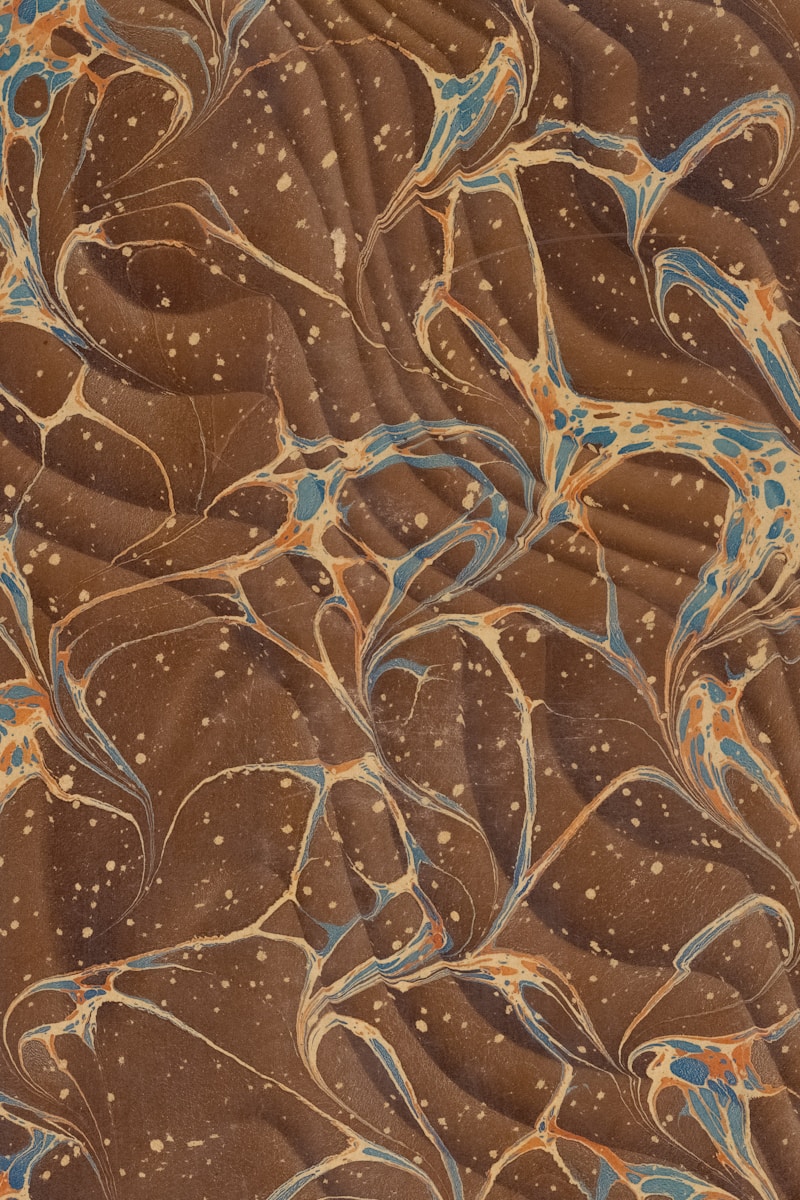Brown marbled paper with blue and orange swirls.